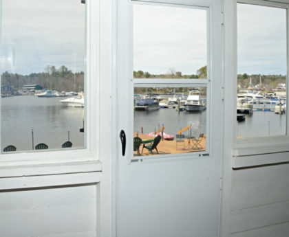 view of water, boats and marina through white storm door in center and windows on each side