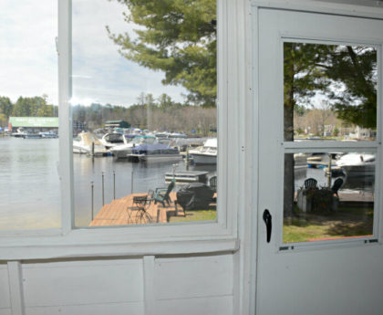 views of water, boats, marina and pine tree through white porch door and window