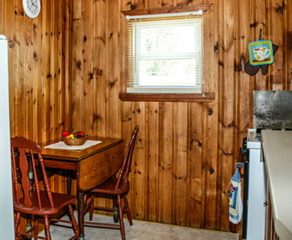 drop-leaf wood table and chairs in corner of kitchen with knotty pine walls