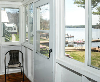 views of water, boats and distant skyline through porch windows and door, one chair in corner