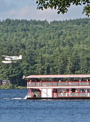 paddle wheeler boat taking passengers on an afternoon cruise as a seaplane passes